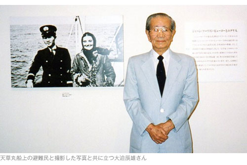 天草丸船上の避難民と撮影した写真と共に立つ大迫辰雄さん